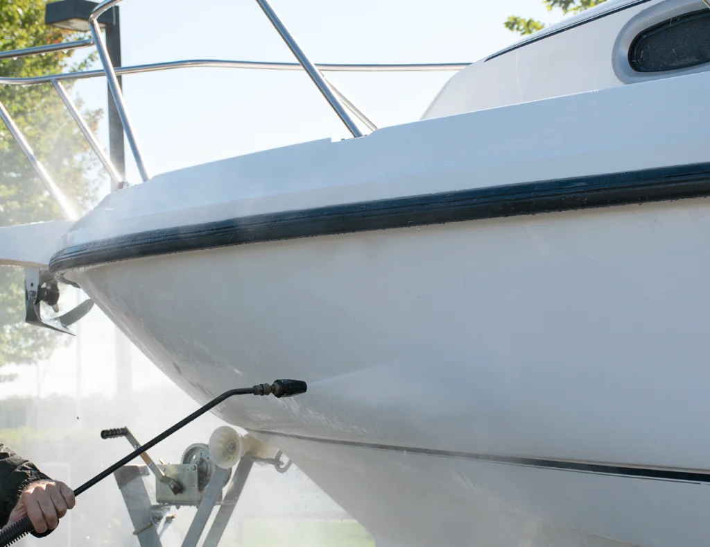 White boat being pressure washed on a trailer